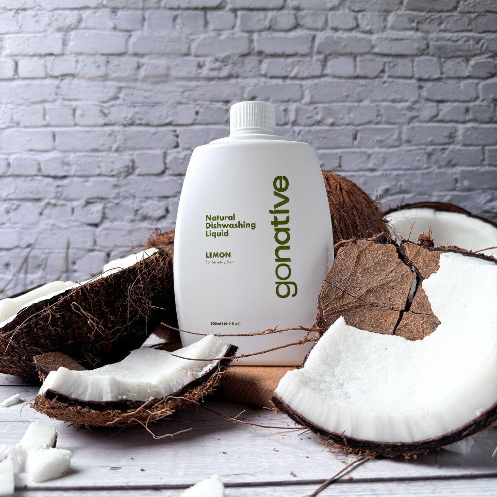 GoNative coconut-based natural dishwashing liquid, lemon, 500ml white refill bottle surrounded by fresh coconuts